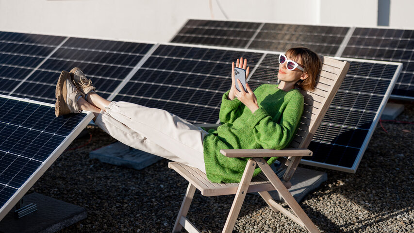 zonnepanelen en een vrouw die in de zon zit met een zonnebril op